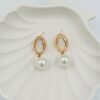 Elegant gold-toned drop earrings with a radiant pearl and white embellishment