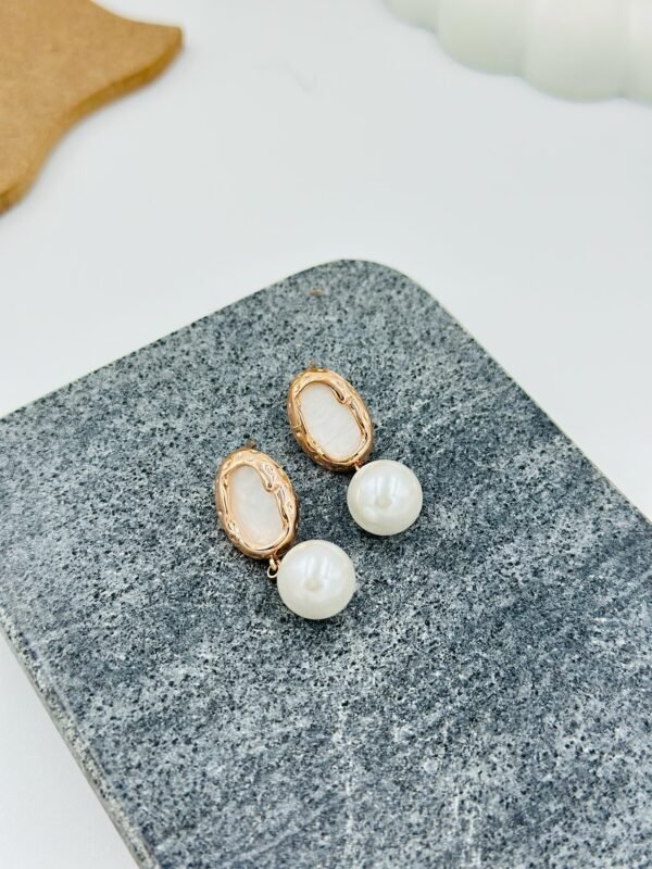 Elegant gold-toned drop earrings with a radiant pearl and white embellishment