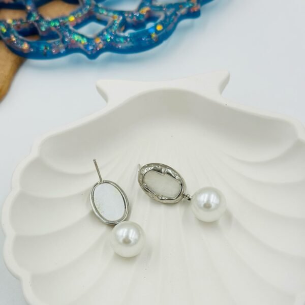 Elegant gold-toned drop earrings with a radiant pearl and white embellishment