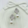 Diamond-studded drop earrings with a radiant pearl